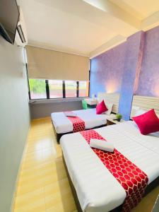 瓜拉丁加奴DJ西提高级宾馆的一间设有三张床和红色枕头的房间