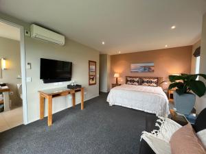 凯库拉马纳考旅舍的一间卧室配有一张床和一台平面电视