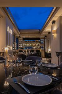 雅典Heritage Hill Hotel的用餐室配有带玻璃杯的桌子