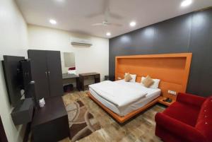 坎普尔Hotel Mandakini Royale Near PVR Deep Cinema Hall Kanpur的一间卧室配有一张床和一张红色的沙发