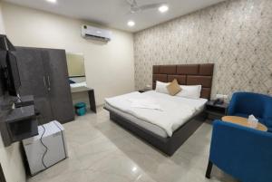 坎普尔Hotel Mandakini Royale Near PVR Deep Cinema Hall Kanpur的一间卧室配有一张床、一台电视和蓝色的椅子