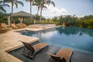 哈普那海滩MAUNA KEA DREAM Dreamy Mauna Kea Home with Heated Pool and Ocean Views的一个带两把椅子的游泳池和一个喷泉