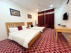 锡卡都Hispar Hotel Skardu的酒店客房配有两张床和一张书桌