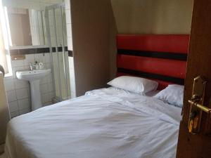 比勒陀利亚Ebony Lounge Hotel and Event Center的卧室配有白色的床和水槽