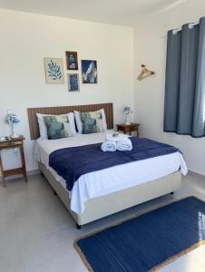 阿拉亚尔-杜卡布Olímpia - Terraço Mykonos com piscina privativa - Casa Grega的一间卧室配有一张床,上面有两条毛巾