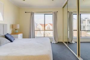 Port AdelaideLuxurious 3 bedroom beachfront - panoramic views的一间卧室设有一张大床和大窗户