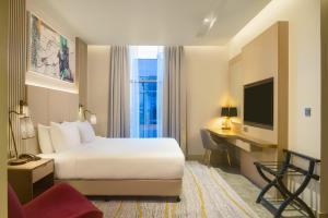 马斯喀特IntercityHotel Bawshar Muscat的酒店客房配有一张床、一张书桌和一台电视。