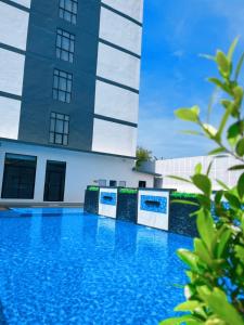 合艾Remas Hotel Hatyai的大楼前的蓝色游泳池