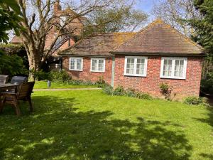 锡廷伯恩Green Cottage in grounds of Grade II* Frognal Farmhouse的院子里的砖屋,配有桌椅