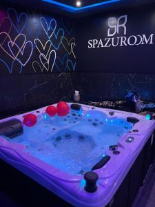 穆斯克龙Spazuroom Luxury Suite的标志前方带灯的按摩浴缸