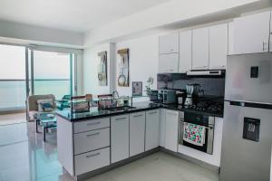 卡塔赫纳Playa Cartagena Apartments的一间大厨房,配有白色橱柜和电器