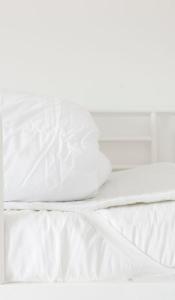海斯勒Nordliv Strand的一张带白色床单和枕头的床