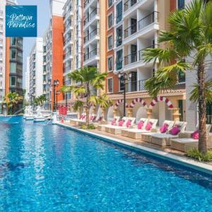 乔木提恩海滩Espana Resort Jomtien Beach Pattaya的一座棕榈树和建筑游泳池
