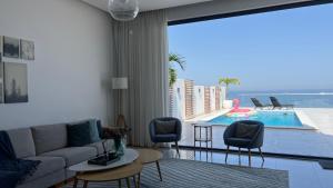 富查伊拉Seascape Villa的带沙发和椅子的客厅以及游泳池。