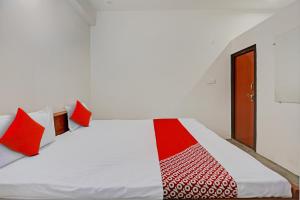 坎普尔OYO Flagship City Light Hotel的卧室配有带红色枕头的白色床
