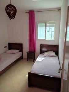 Aït SaïdFerme Abdou的一间卧室设有两张床,窗户配有粉红色的窗帘