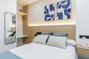 马拉加Stay Belonio的一间卧室配有一张带蓝色和白色枕头的床