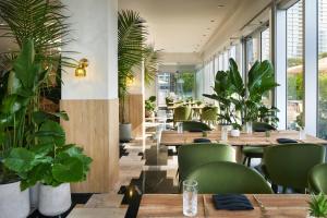 迈阿密W迈阿密酒店的餐厅设有木桌和绿色椅子,种植了植物