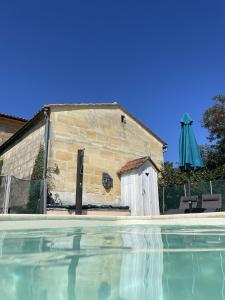 Saint-Pey-de-CastetsCinégîte du jardin aux étoiles - Proche de Saint Emilion的一座带遮阳伞的游泳池旁的建筑