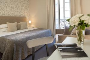 雷恩Le Nemours Rennes的一间卧室配有一张床和一张花瓶桌子