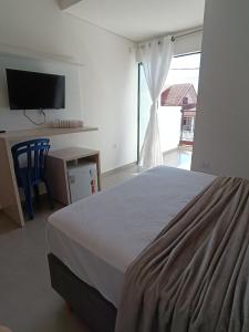 巴拉那州蓬塔尔Residencial Mar Azul-suíte 12的一间卧室配有一张床、一张书桌和一台电视