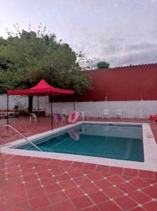 AreguáCasa de la Amistad的一个带红伞和红色建筑的游泳池