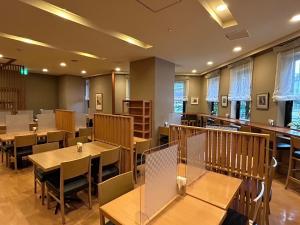 盛冈盛冈站前干线酒店的餐厅设有木桌、椅子和窗户。