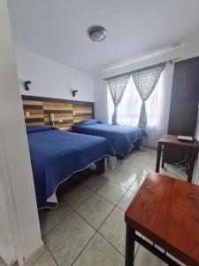 阿里卡Kunturi Guest House的一间卧室配有两张床、一张桌子和一张长凳