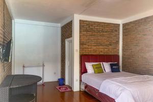 BanjarnegeriUrbanview Hotel Villa Q Gisting的一间卧室设有一张床和砖墙