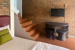 BanjarnegeriUrbanview Hotel Villa Q Gisting的一间卧室设有楼梯、桌子和电视