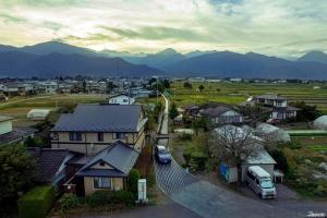 安昙野市Shino's Farm Inn的山前有房屋和货车的村庄