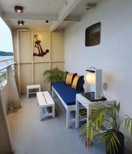 拉古洼Doulos Phos The Ship Hotel的客房设有蓝色长椅、桌子和电视。