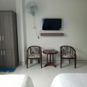 大叻Tường Lan Hotel的一间设有两把椅子、一张桌子和一台电视的房间