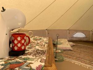 帕达斯特Pädaste Aerga Sunrise Glamping的一张桌子上的一个红色咖啡杯,放在一个帐篷里