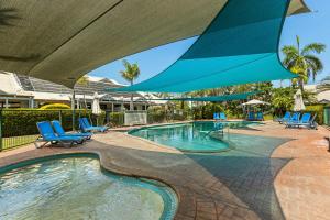 布鲁姆Cable Beach Apartments的一个带蓝色椅子和大伞的游泳池