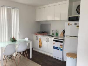 奥克兰West Auckland Delight Stay的厨房配有白色橱柜、桌子和冰箱。