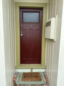 惠灵顿Cosy Coastal Villa in Lyall Bay的房屋前有标志的红色门