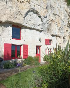 蒙索罗Gite des Perreyeurs - maison troglodyte avec vue sur Loire的石头房子,有红色的窗户和岩石墙