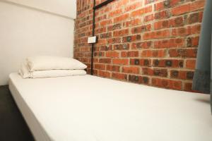 瓜拉丁加奴18套房精品酒店的卧室设有砖墙和白色床垫。