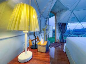 Ban Na Pa Paekสวนไร่รุ่งอรุณ的一间帐篷内带床和灯的房间