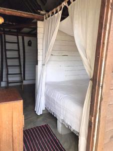 MahamboBeach front Cottage的一间卧室配有一张带天蓬和梯子的床
