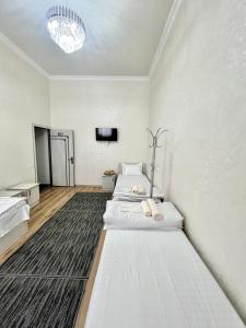 撒马尔罕MrShox Hostel的白色客房的两张床,配有电视