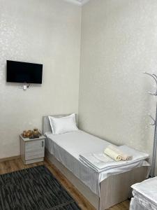 撒马尔罕MrShox Hostel的一间小卧室,配有一张床和一台墙上的电视