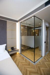 伏罗拉Belvedere Hotel的一间卧室配有带玻璃墙的淋浴和一张床