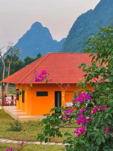 峰牙Phong Nha Eco Village的一座橙色房子,前面有紫色的鲜花