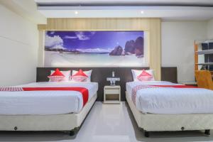 登巴萨Super OYO Balitone Residence的墙上画画的房间里设有两张床