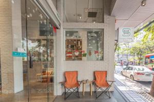 曼谷Simply Sleep Hostel的两个橙色椅子坐在商店外面