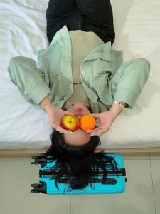 三宝垄Gapura Residence Airport Semarang by Sinergi的女人在床上拿着水果