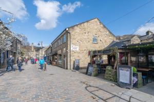 HebdenPass the Keys Family Haven -Amazing Views-Heart of Hebden Bridge的一群人沿着鹅卵石街道走着