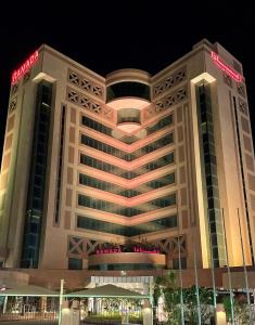 布凯里耶Ramada Hotel & Suites by Wyndham Al Qassim的一座大建筑,晚上有标志